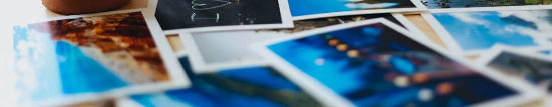 Fotobok med tre bilder på omslaget, liggande på träbord bredvid en svart kamera